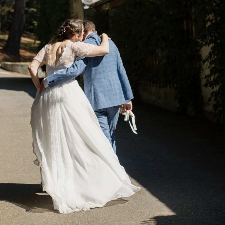 Un couple de mariés se tient par l'épaule en marchant sur un chemin. L'amour